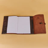 An open leather-bound notebook with lined white pages, displayed flat against a solid beige background.
