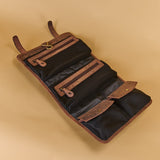 A brown leather and black mesh multi-pocket organizer roll, shown open to display its compartments, straps, and zipper pockets, set against a solid beige background.