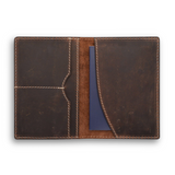The Vintage Leather Passport Wallet - Perth, shown open on a white background, displays two pockets for organisation on the left and a blue passport partly tucked on the right—an ideal travel accessory with visible stitching and brown leather finish.