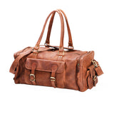 The Leather Duffle Bag - Colorado by Vintage Leather Sydney features brown handmade leather, gold-tone buckles, two handles, a shoulder strap, front and side pockets, and a structured rectangular shape—ideal for stylish travel.