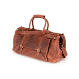 A brown distressed leather duffel bag with dual top handles, a detachable shoulder strap, and brass-tone buckle details, shown on a plain white background.