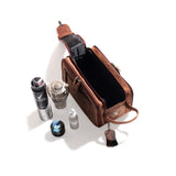 The Leather Travel Toiletry Bag Porter by Vintage Leather Sydney sits open on a white surface, surrounded by a can of deodorant, a small jar, a clear glass container, a dropper bottle, and a round tin.
