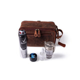 A Leather Travel Toiletry Bag Porter by Vintage Leather Sydney is placed behind a can of Rexona deodorant, a small black jar, a clear dropper bottle, and a glass mug with metal lid on a white background.