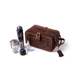 The Leather Travel Toiletry Bag Porter by Vintage Leather Sydney is shown on a white background, accompanied by a glass mug, deodorant spray, small jar, dropper bottle, and toothbrush.