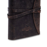 The Indigo Journal Leather by Vintage Leather is a dark brown vintage buffalo leather journal with a wraparound strap and an embossed helmet logo on the cover. Personalisation available for a unique touch.