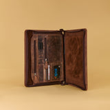 A dark brown leather organizer case shown open, revealing interior card slots, pen loops, and a small blue LED display, set against a solid beige background.