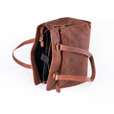 The Leather Handbag Fennel by Vintage Leather Sydney is shown open, displaying its spacious interior with a zippered pocket and padded strap. Featuring two handles and side metal buckles, it’s ideal for carrying travel essentials.