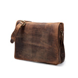 The Vintage Leather Laptop Bag Jersey, in brown leather with a buckle, zippered side pocket, and adjustable shoulder strap, is shown closed and upright on a white background with a rustic, worn look.
