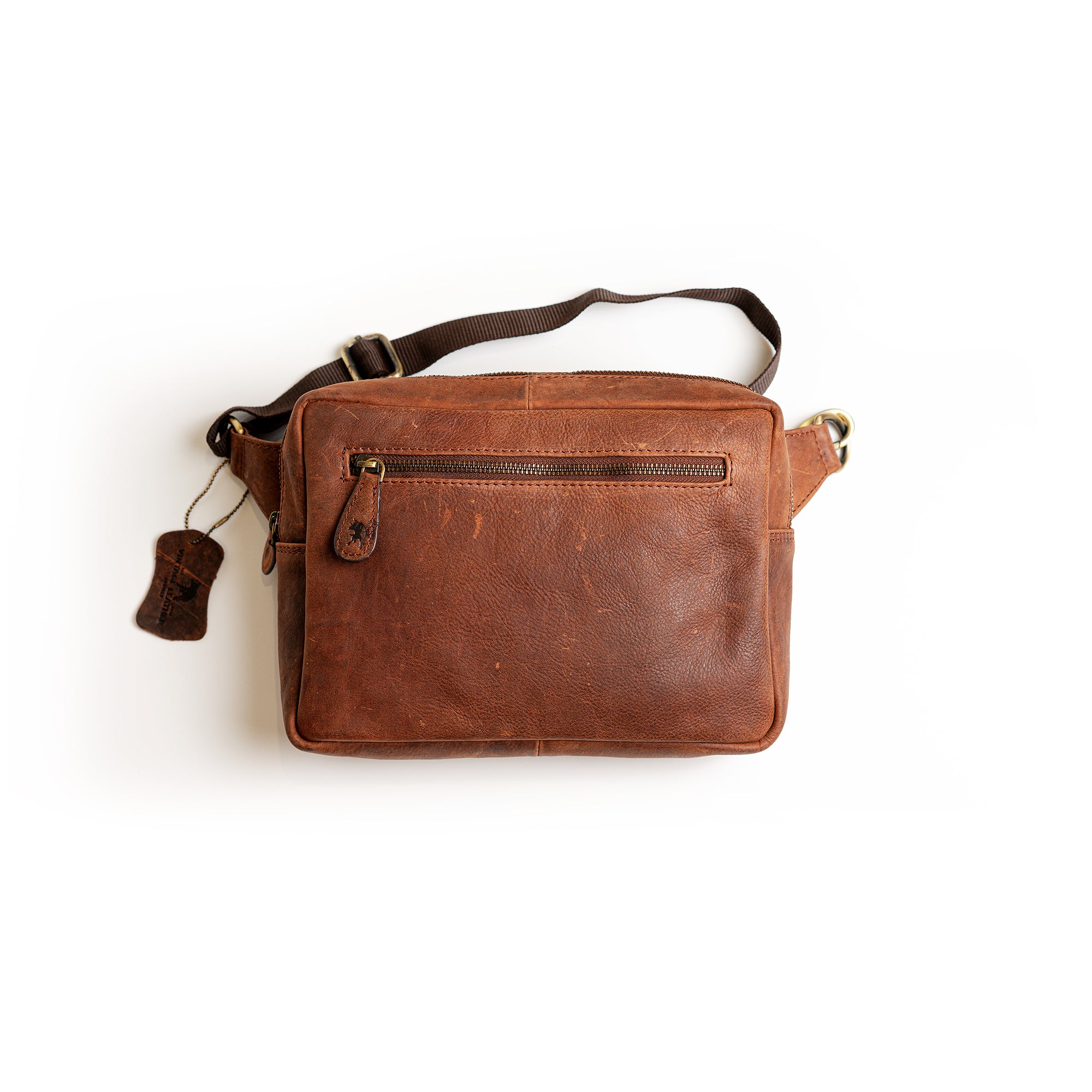 The Leather Sling Bag Akiva by Vintage Leather Sydney features a brown leather design with a front zipper pocket, adjustable dark strap, and a small side tag—perfect for stylish women seeking modern sling bags.