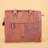A brown distressed leather tote bag with gold-tone hardware, featuring a front zippered pocket and top handles, set against a solid beige background.