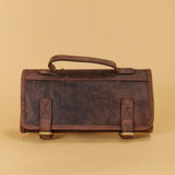 A dark brown distressed leather tool roll with a top handle and two front strap closures, shown against a solid beige background.