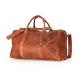 A brown leather duffel bag with dual top handles, a detachable shoulder strap, and brass-tone hardware, photographed on a clean white background.